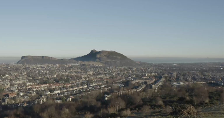 A view of Edinburgh, Scotland, with the Salisbury Crags in the background on a sunny day