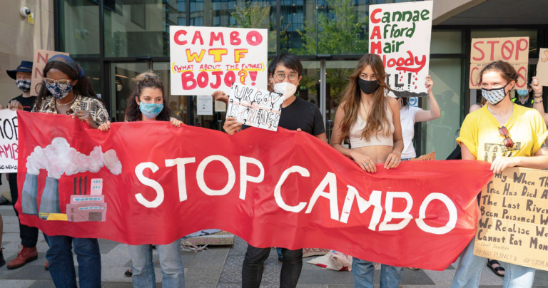 Protestors against the proposed Cambo oil field in Scotland holding signs and a red banner reading "Stop Cambo"