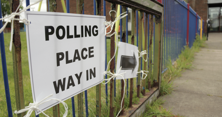 A sign attached to multicoloured school railings directing people to a polling place for Scottish elections